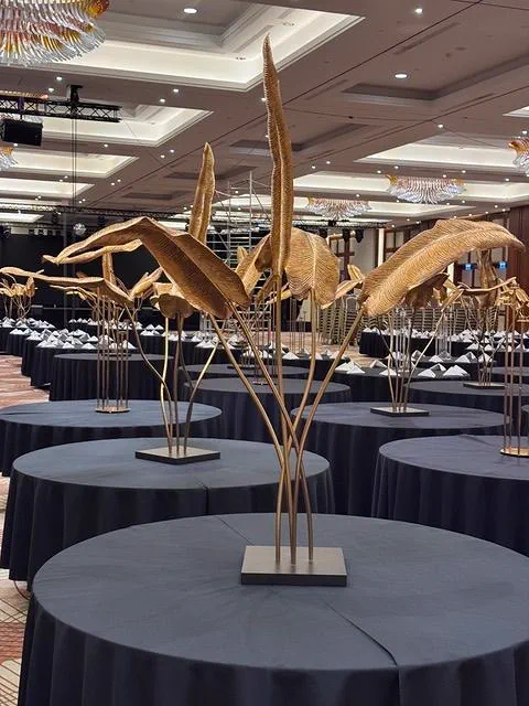 Dekoracja wykonana ze złotych liści bananowca ustawionych na stołach przykrytych czarnymi obrusami