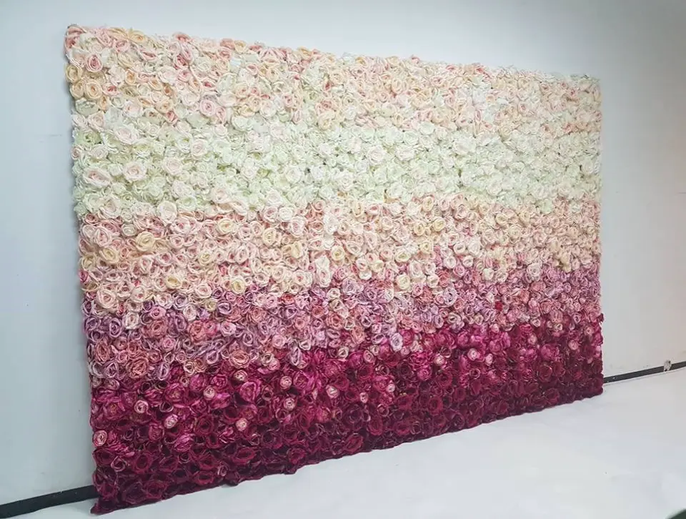 Ścianka kwiatowa w stylu ombre, złożona z gęsto ułożonych sztucznych róż w odcieniach od bieli przez pastelowy róż aż po głęboki burgund. Elegancka dekoracja eventowa idealna na wesele, przyjęcie urodzinowe, sesję zdjęciową czy tło do fotobudki. Gradientowy układ kwiatów nadaje aranżacji romantyczny i luksusowy charakter, przyciągając uwagę